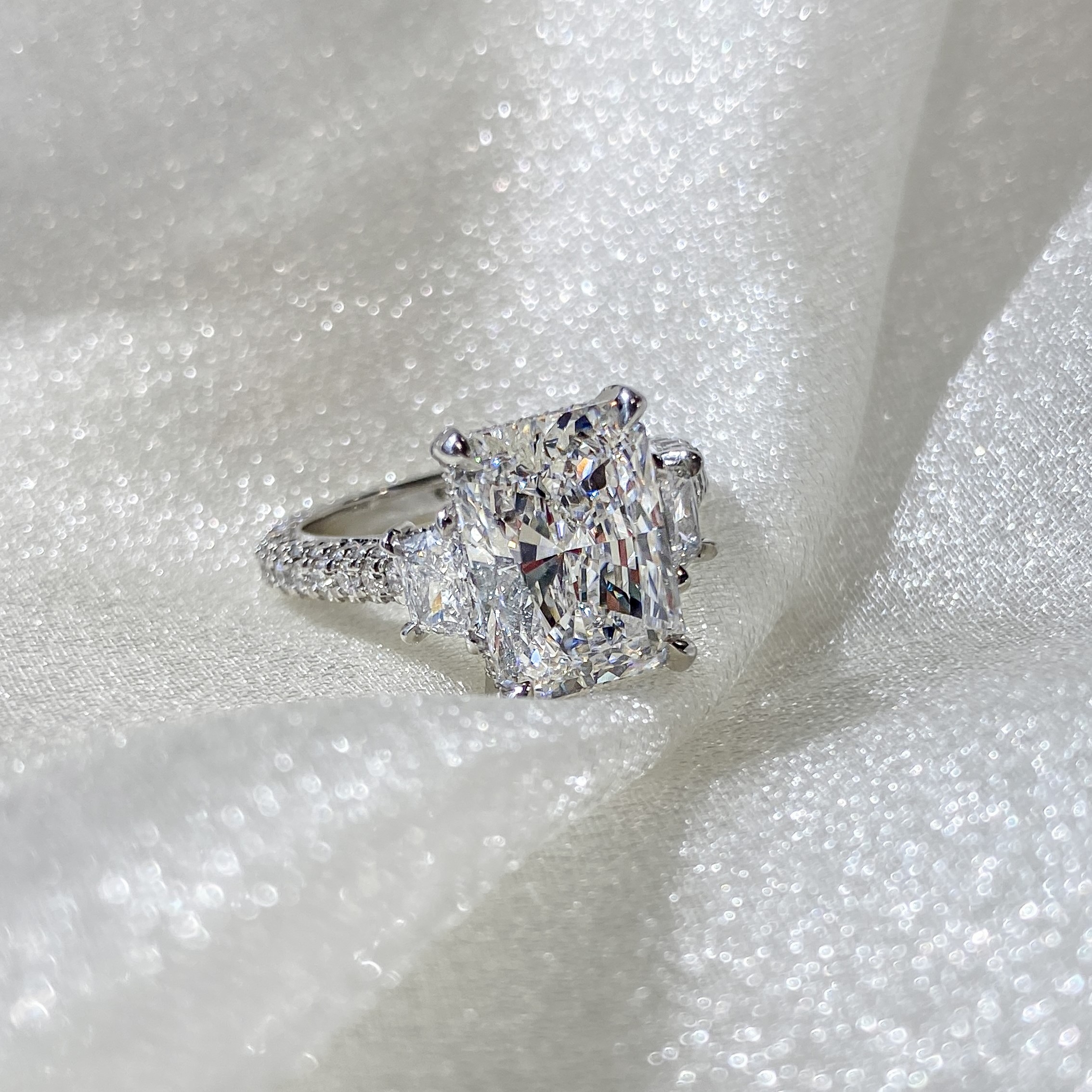 radiant cut three stone ring on sparkly fabric