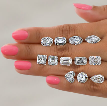 ladies hand wearing three radiant cut engagement rings and diamond eternity bands